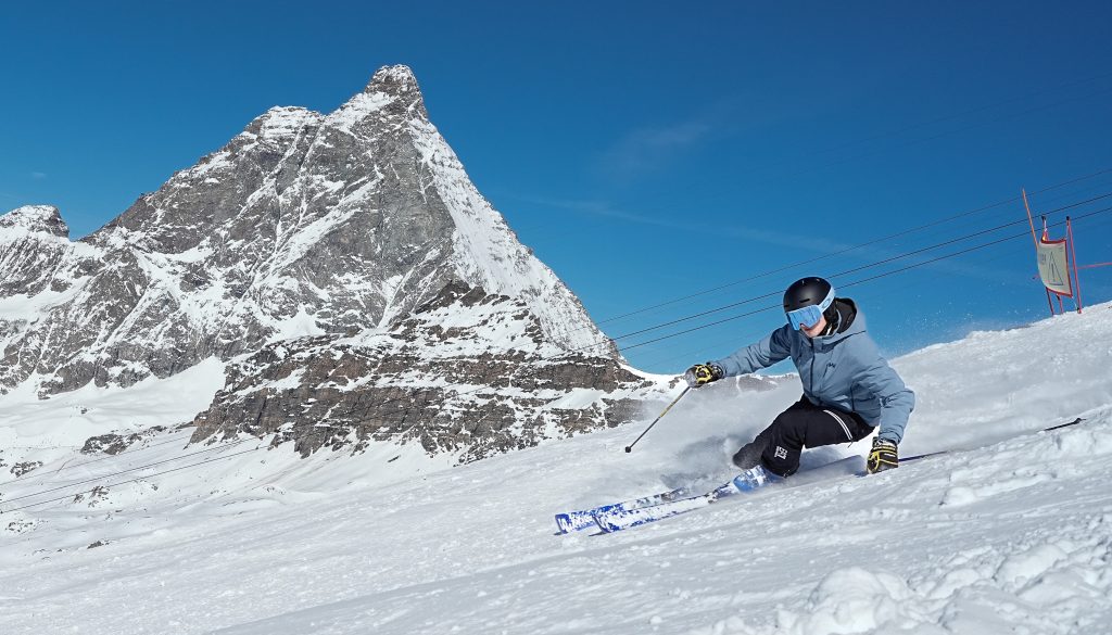 Un skieur en plein virage sur les pistes de Cervinia, avec le Cervin en arrière-plan