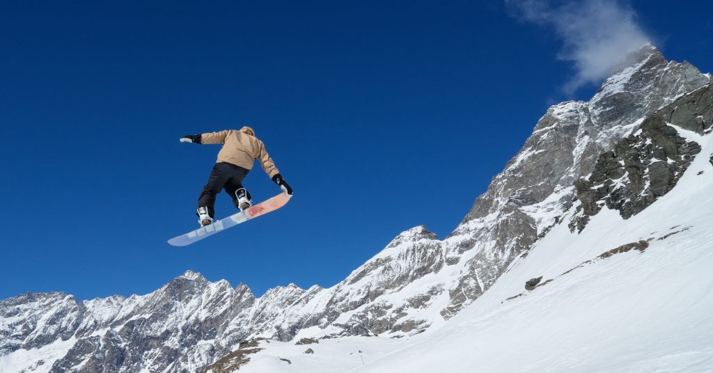Un snowboardeur en plein saut dans le snowpark de Cervinia, avec le Cervin en arrière-plan